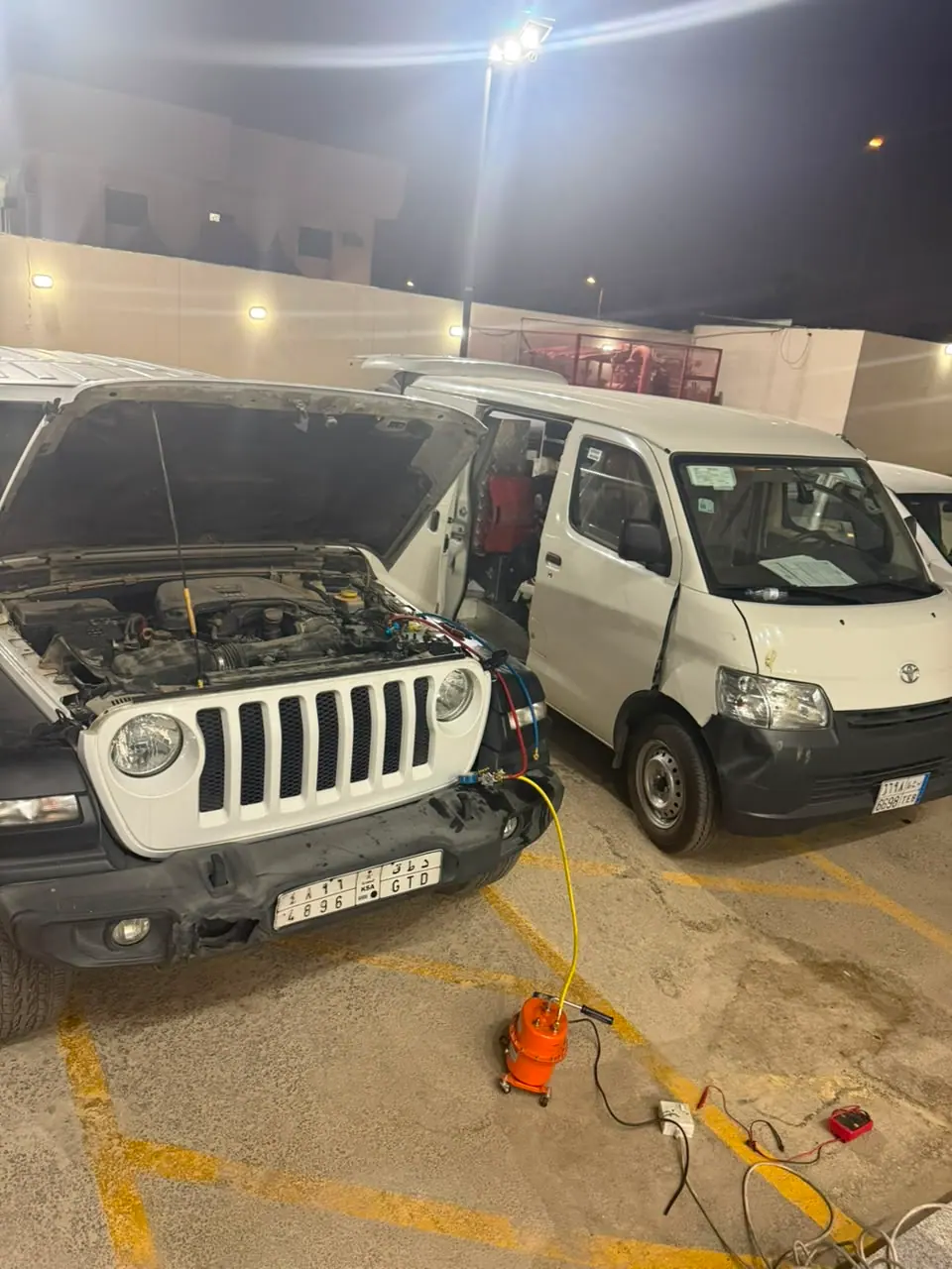 Car AC gas recharge at night on a white Jeep Wrangler in Riyadh using the Saaed Service AC machine