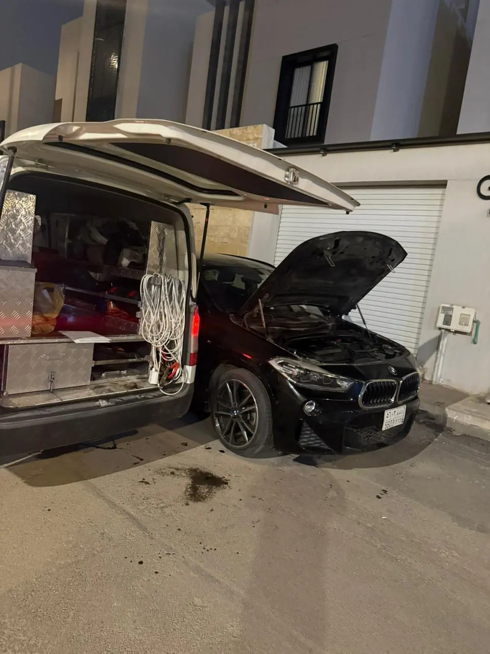 Saaed Service attending a black BMW X2 at night outside a Riyadh home