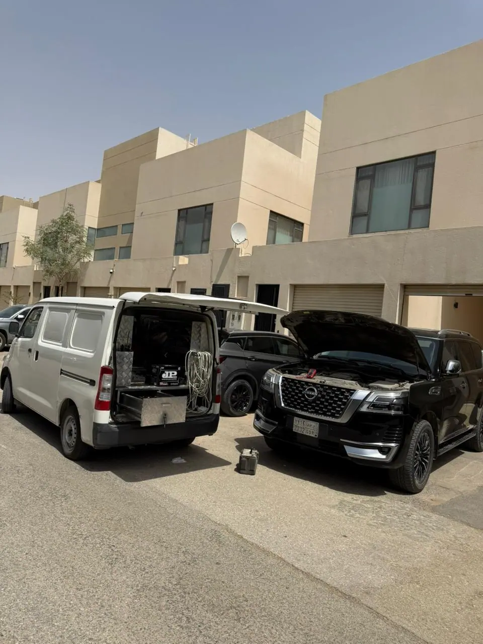 Saaed Service van and a black Nissan Patrol with the bonnet up on a Riyadh residential street