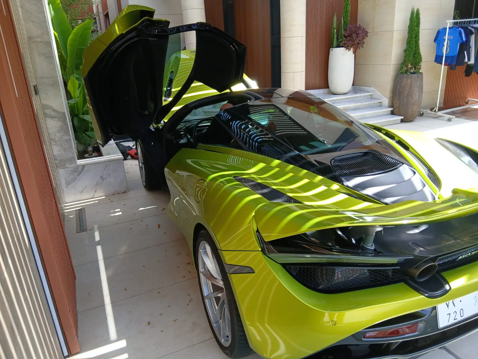 Saaed Service attending a lime-green McLaren 720S with its door raised at a Riyadh villa