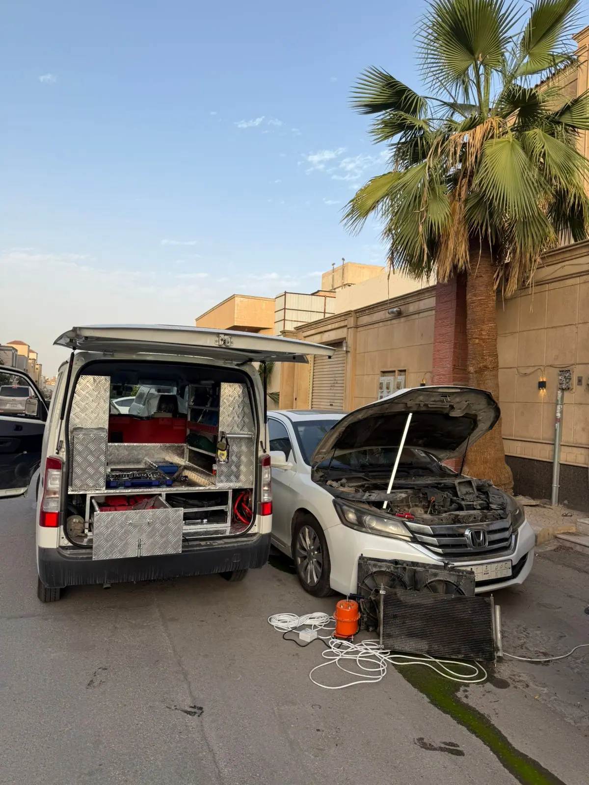 Radiator and condenser removed from a white Honda Accord on a Riyadh street beside the Saaed Service van
