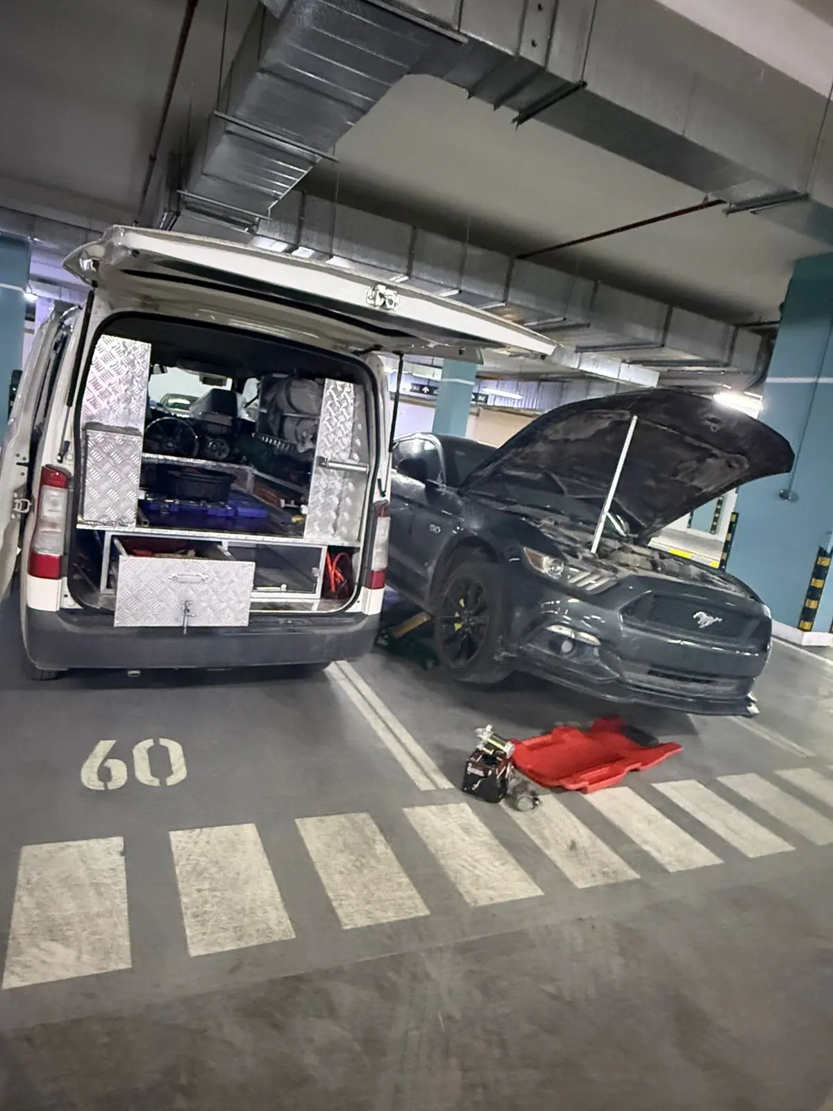 A Saaed Service technician in branded uniform working under the bonnet of a white Mercedes-Benz GLK in Riyadh